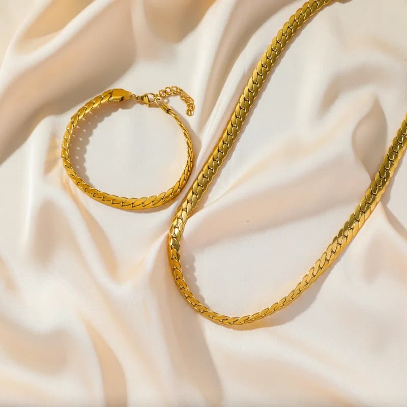 Sætte med fladt bredt kædehalssmykke og armbånd i guld